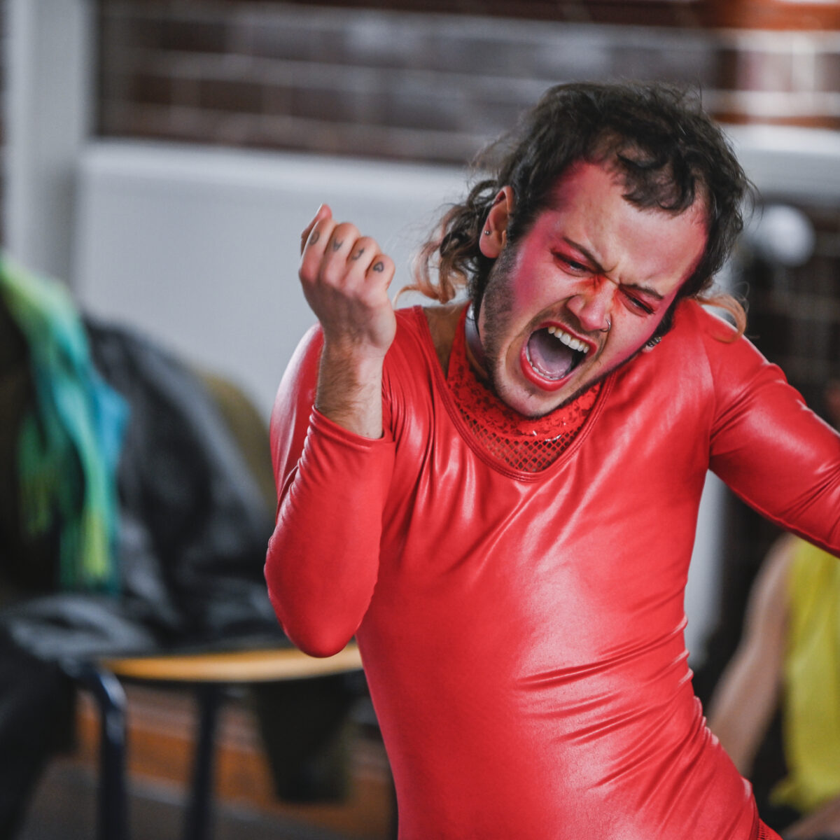 Dani Diger dances whilst wearing a neon pink long-sleeved latex outfit.