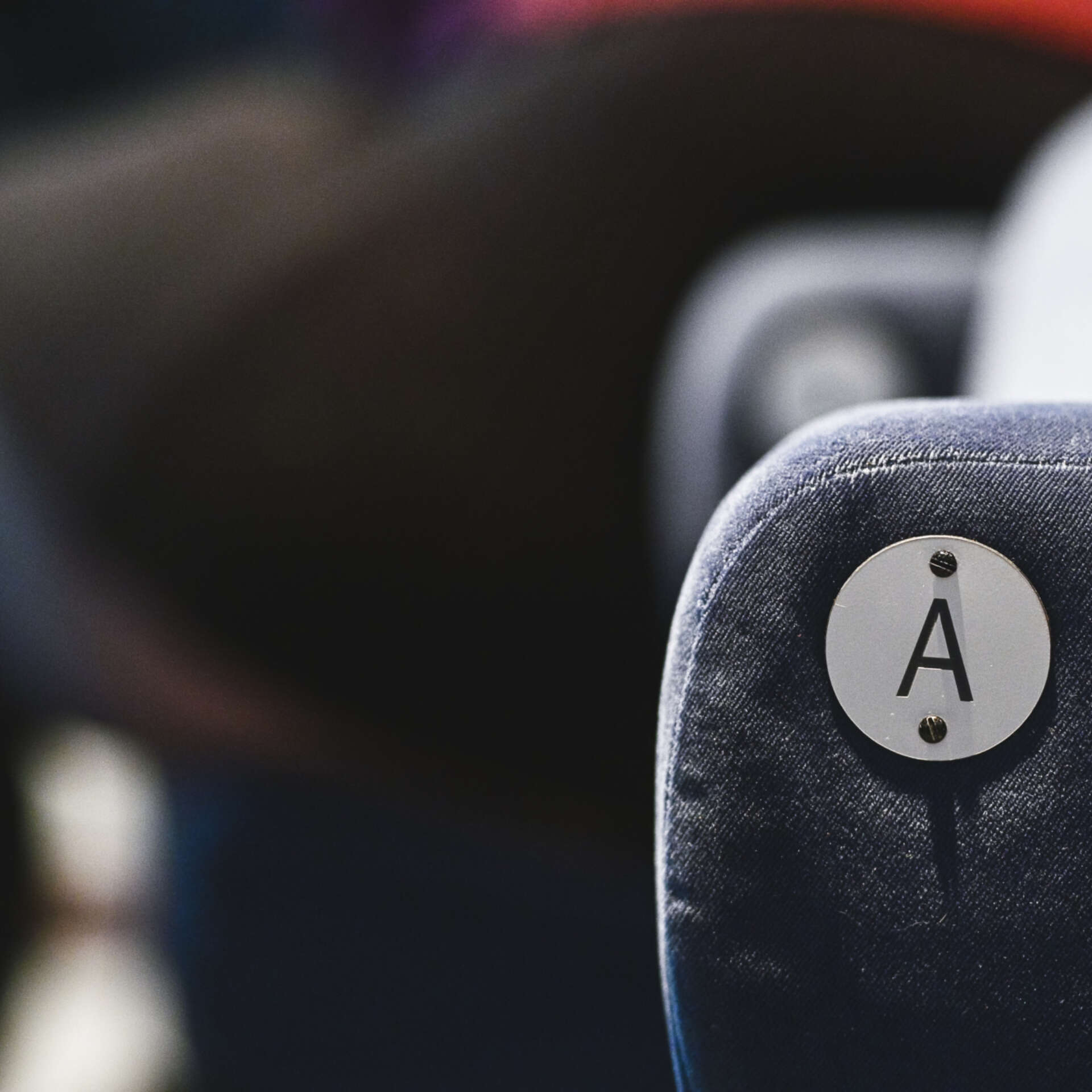 The back of a navy velour cinema seat with the letter A on the back left.