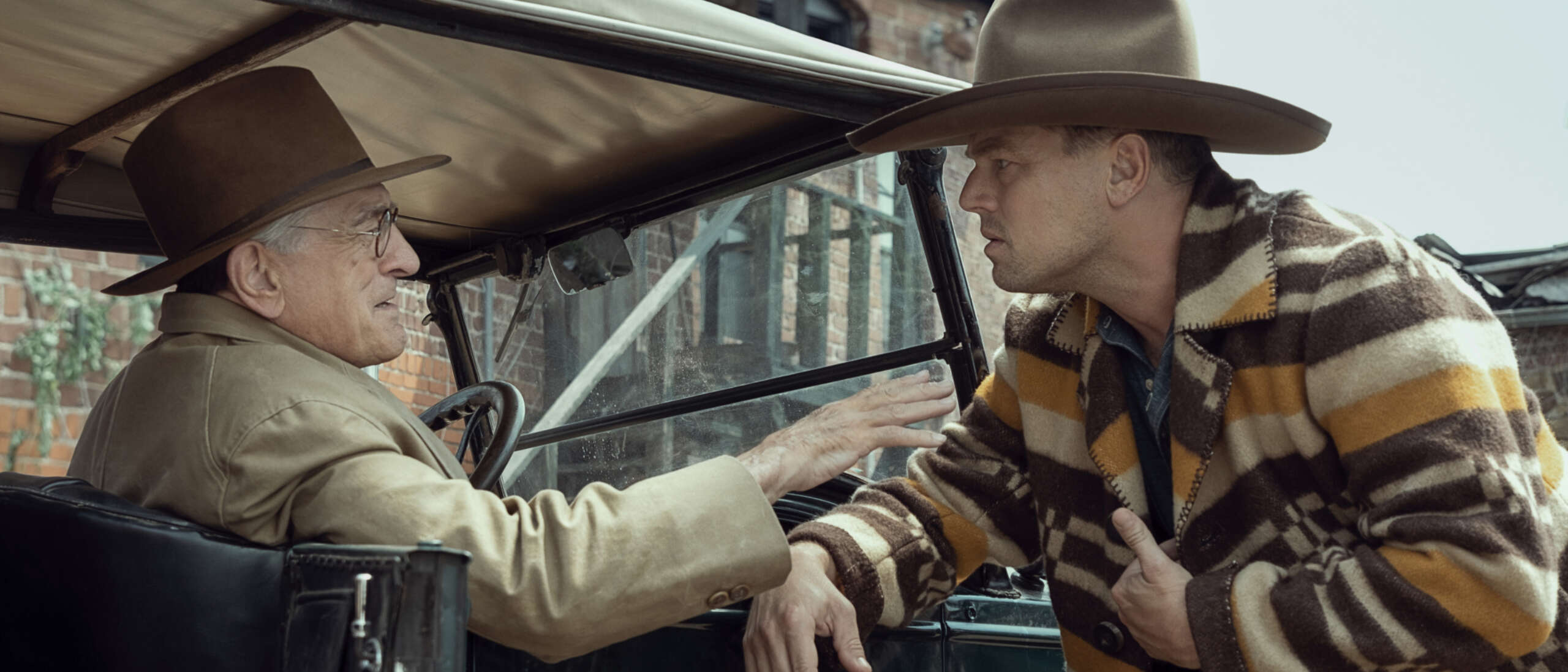 Robert DeNiro and Leonardo DiCaprio talk to each other in a 20s themed film set. Still image from Killers of the Flower Moon.
