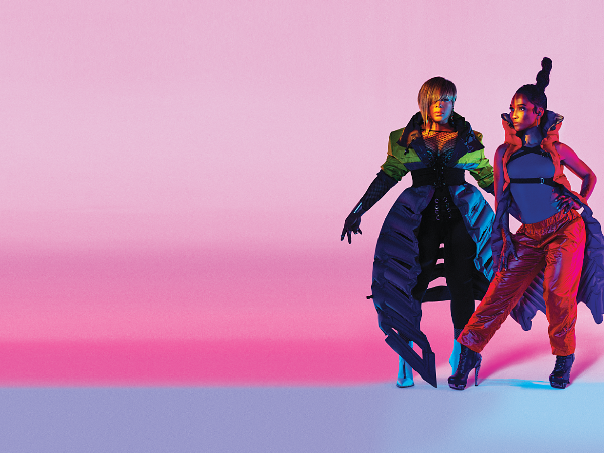 Girl group TLC pose for a photograph against a neon pink background.